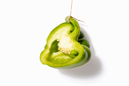 Cross section of green pepper hanging on a jute string, \npepper seed nest. Green peppers are very healthy, rich in chlorophyll, have many health-promoting properties and are worth eating raw.