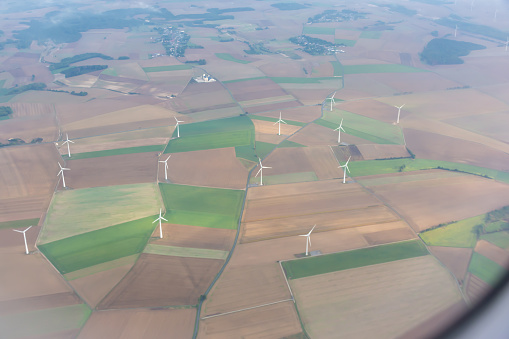 An aerial view of wind turbines in a vast plain, creating a unique landscape against the horizon. The turbines flap like wings in the ecoregion