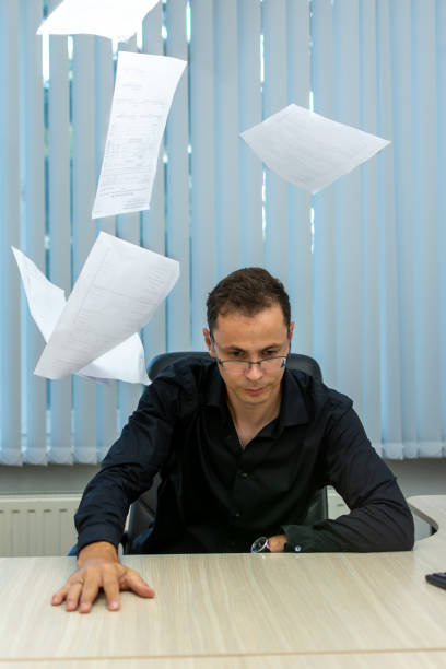istock a man sitting at a desk with papers falling around him 2149550095