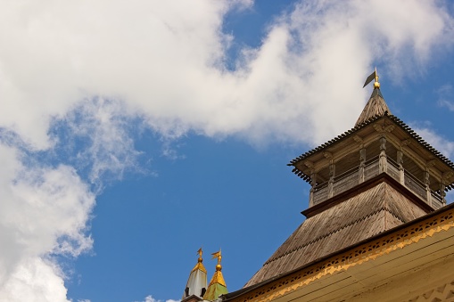 Magnificent view of the wooden roof of an ancient watchtower in the Rostov Kremlin, observation post and hipped roof with a weather vane, fragment of a wall, ancient Russian architecture, history and culture, sky and clouds, cityscape, gilded details, summer.