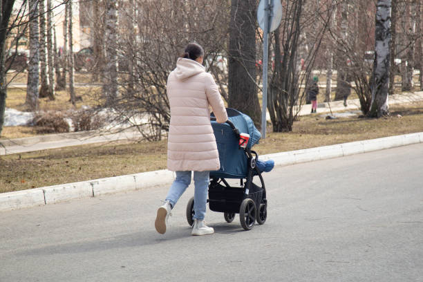 Syktyvkar, Komi Republic, Russia, April 21, 2024,A woman with a baby in a stroller walks through the park.