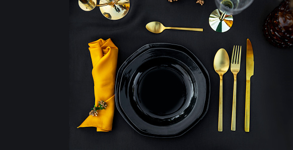 Elegance table setting in black and gold color. Close up, flat lay. Copy space on left