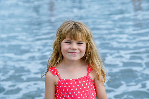 Portrait of Happy Child, Little Preschool Girl in Swimmsuit Running And Jumping In The Waves During Summer Vacation On Exotic Tropical Beach. Family Journey On Ocean Coast