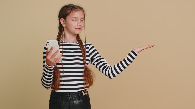 child girl kid with mobile smartphone showing pointing empty place, advertising area, copy space