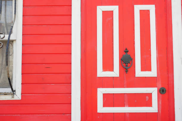 Red door framed by symmetrical geometric patterns in crisp white creating striking contrast.