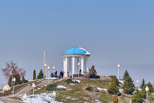 Almaty, Kazakhstan - March 17, 2024: Close-up of an observation deck with a rotunda on the top of an artificial hill. Park of the first president of the republic. Winter landscape. Copy space