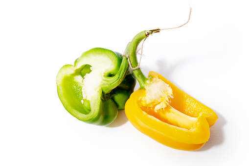 Green and yellow pepper on the white background with\npepper seed nest.