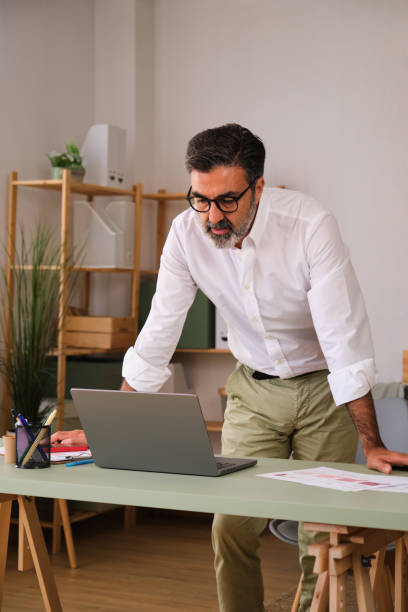 istock A man is standing in front of a laptop computer, looking at the screen. 2149557127