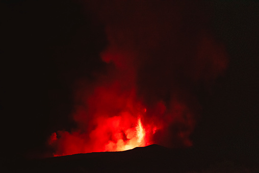 Etna paroxysm, with very high black cloud and fire fountains tens of meters high and lava flows, in the night