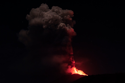 Etna paroxysm, with very high black cloud and fire fountains tens of meters high and lava flows, in the night