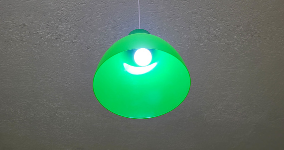 A bright green lampshade with a light bulb hangs from the ceiling