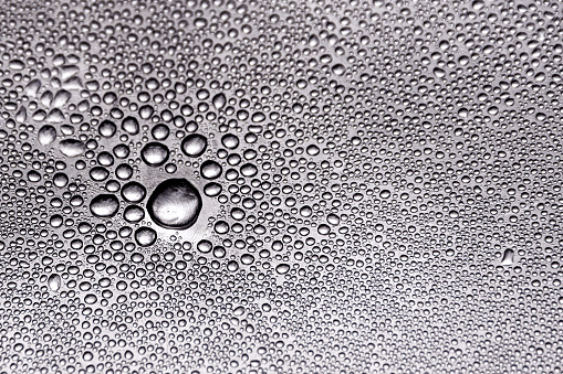 Gray water-repellent fabric for furniture or clothing, with moisture drops. Artificial surface. Modern nano-leather or eco-leather. Textured background or backdrop. Selective focus. Close-up. Macro.