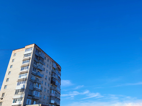 The facade of a high-rise semicircular house with balconies on a blue sky background.