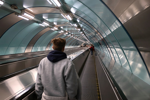 A man descends on a metro escalator with futuristic tunnel design.