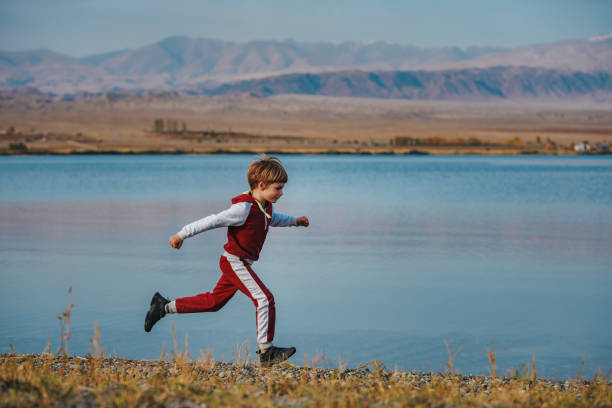 Active boy running on the lake shore