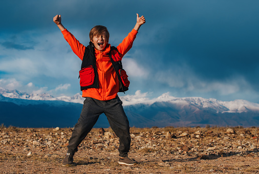 Happy emotional boy tourist on mountains background at autumn