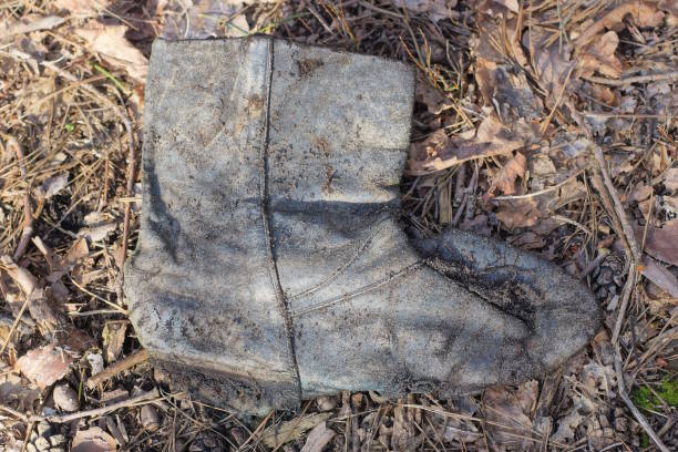 one old gray dirty leather boot lies on the ground on the street