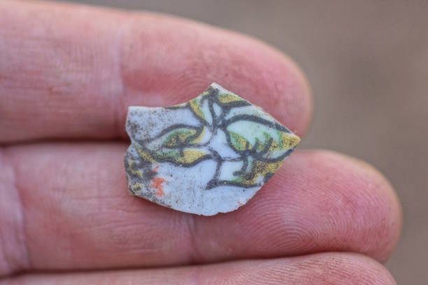 istock hand holding a piece of small old ceramic tile with color pattern 2149577485