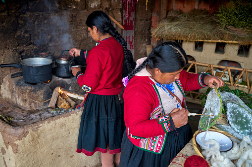 Indigenous women from the Chinchero town of Peru preparing natural materials to dye the threads that will create the fabrics