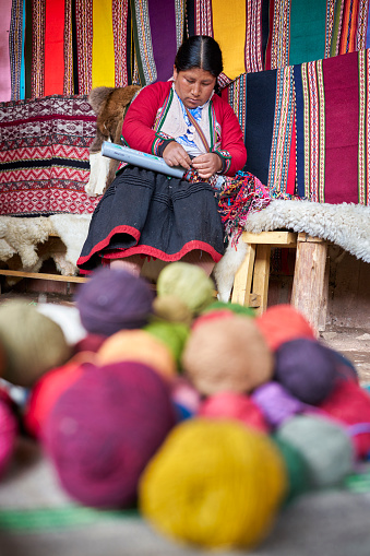 Indigenous woman weaver from the Peruvian town of Chinchero selecting colored threads made with alpaca hair