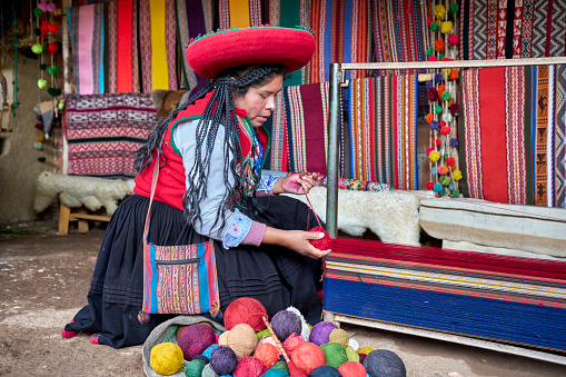 Chinchero indigenous woman stretching the threads that will form the fabric made with alpaca animal hair