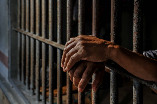 istock hands of a prisoner behind prison bars 2149578294