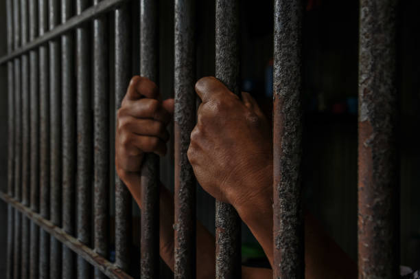 istock hands of a prisoner behind prison bars 2149578307