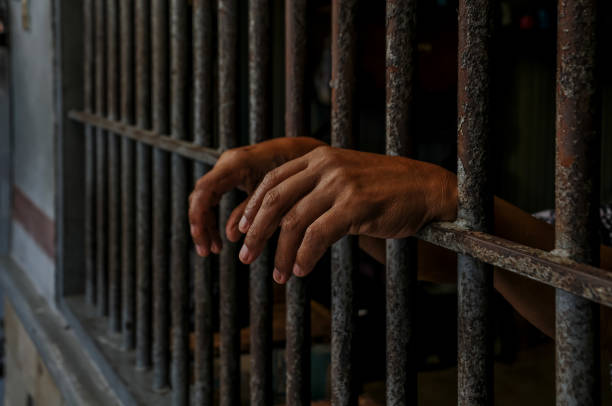 istock hands of a prisoner behind prison bars 2149578335