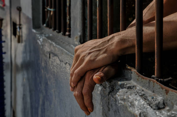 istock hands of a prisoner behind prison bars 2149578458