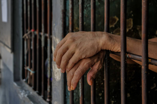 istock hands of a prisoner behind prison bars 2149578476