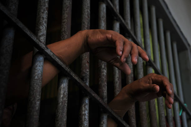 istock hands of a prisoner behind prison bars 2149578490