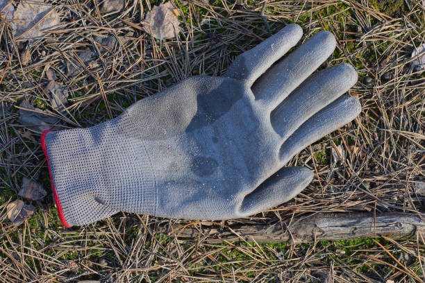 one old dirty work glove made of gray fabric lies on the ground in the street