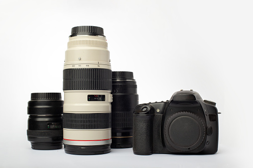 DSLR digital SLR camera with a set of lenses including macro, tele and wide angle, isolated on a white background