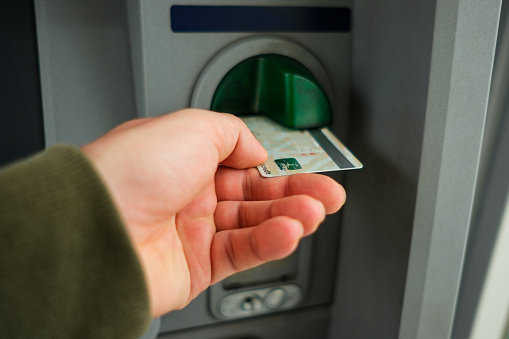 Close-up photo of hand inserting credit card into ATM