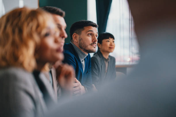 A Happy Handsome Businessman Working With His Team In The Office A wide angle view of a pensive Caucasian entrepreneur listening carefully to some colleagues while being at some business meeting. blue business stock pictures, royalty-free photos & images