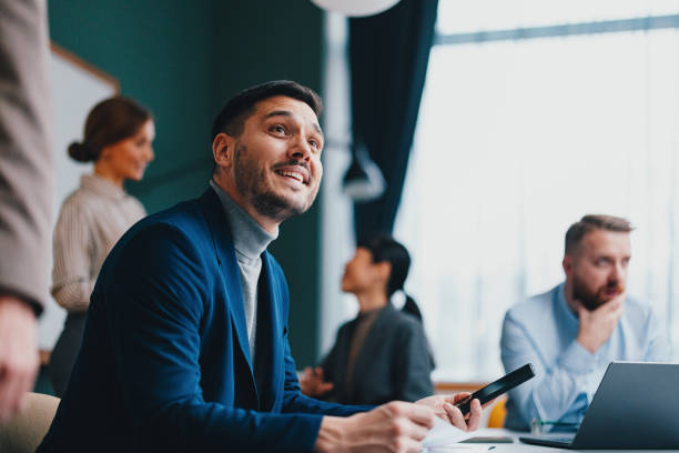 A Happy Beautiful Businessman Looking Away While Working In The Office A smiling Caucasian entrepreneur contemplating some business ideas while sitting at the office desk. blue business stock pictures, royalty-free photos & images