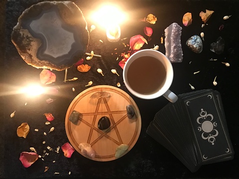 a table with candles and crystals with a cup of tea and a deck of tarot cards