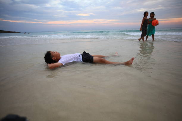 Young child experiencing ocean waves splashing onto the sandy beach