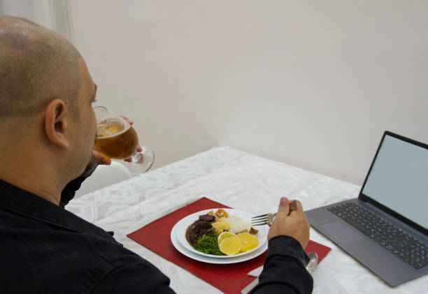 istock Close-up back view of a man having dinner and looking to computer 2149587629
