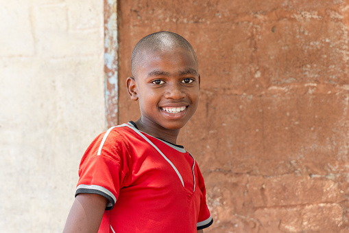 smiling african villager child playing outdoors in front of the house in a village,