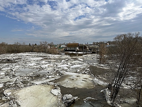 flood on the river in spring. ice floes float on the river against the background of a blue sky with clouds.