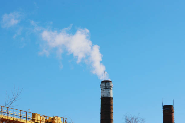 Two factory chimneys with smoke against a clear sky.  Environmental pollution concept.