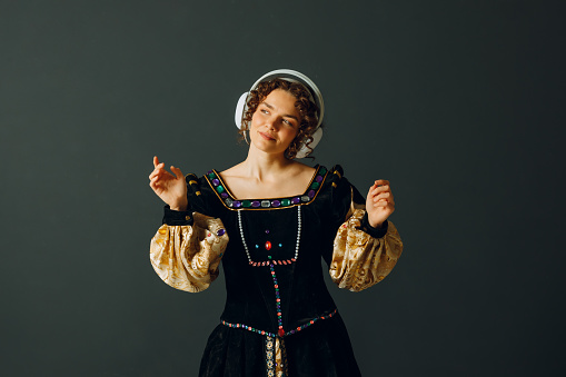 Portrait of a young woman with headphones on her head and dressed in a vintage dress listens music