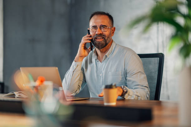 istock Mature executive at corporate office talking on the phone with clients 2149591490
