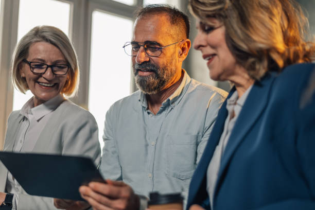 istock Mature managers smiling at tablet and collaborating on project at office 2149591495