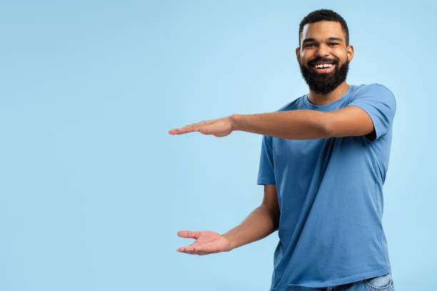 istock Smiling African American man pointing away side with hands over blue background with copy space 2149592430