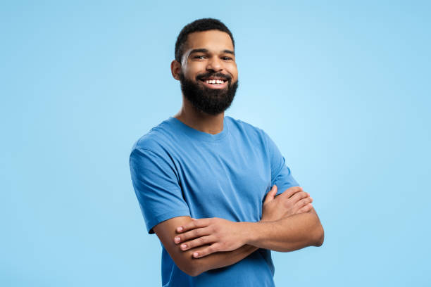 Smiling African American man with arms folded over blue background with copy space. Advertisement concept