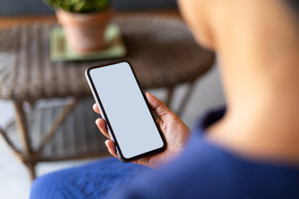 istock Over the shoulder shot of woman using smartphone with blank white screen 2149592512