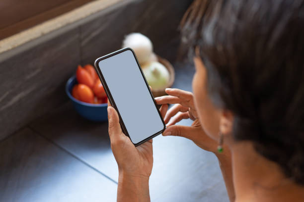 istock Over the shoulder shot of woman using smartphone with blank white screen 2149592616