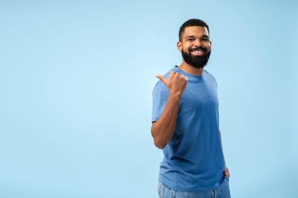 istock Happy young African American man pointing to copy space with thumb up 2149593381